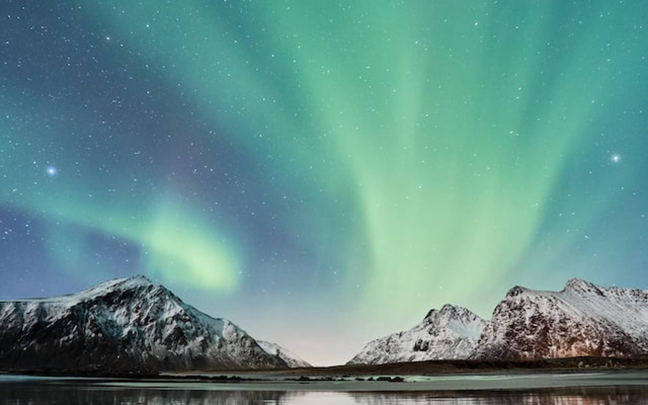 Northern lights and stars over mountains and lake