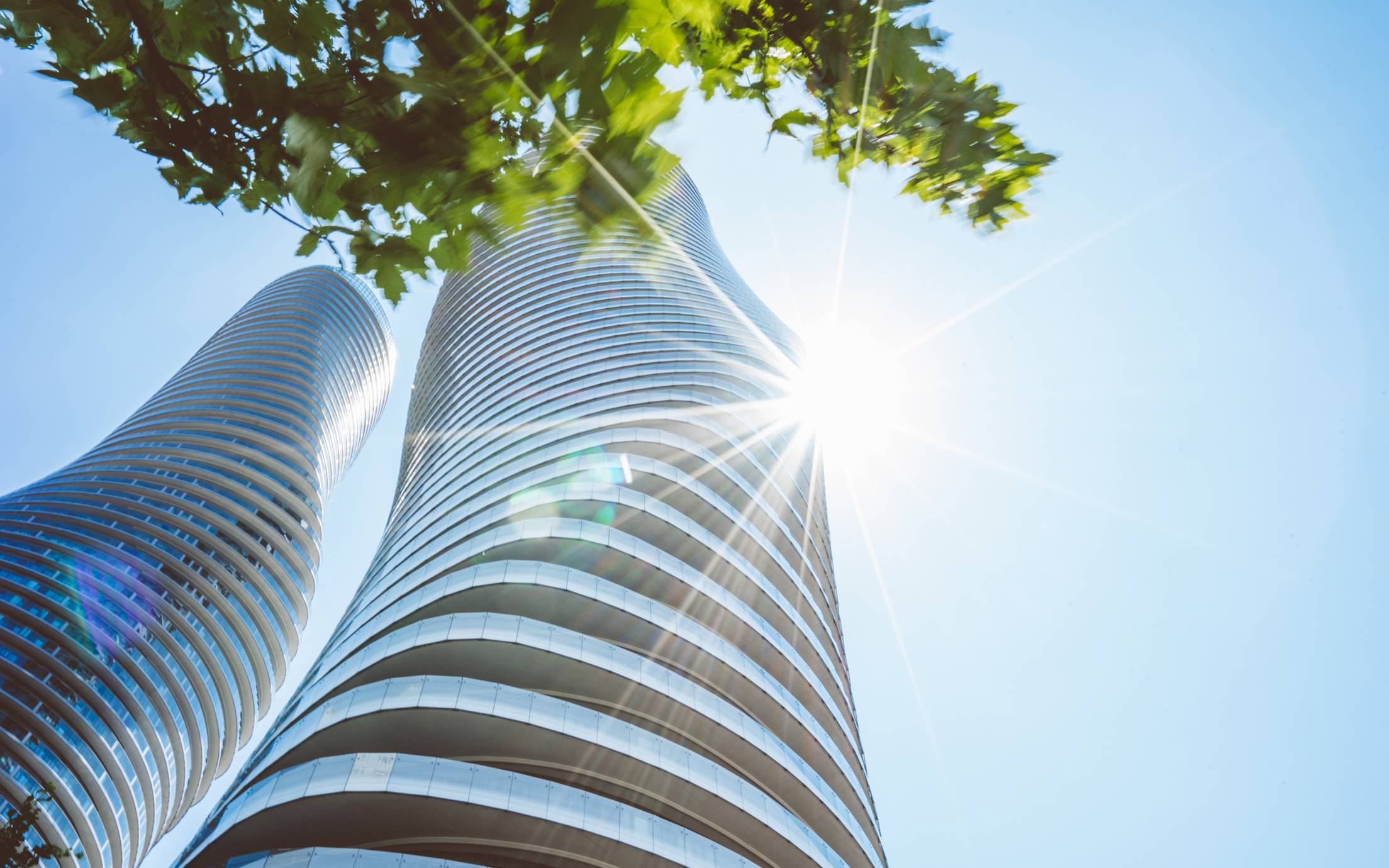 Two tall glass buildings covered in sunshine