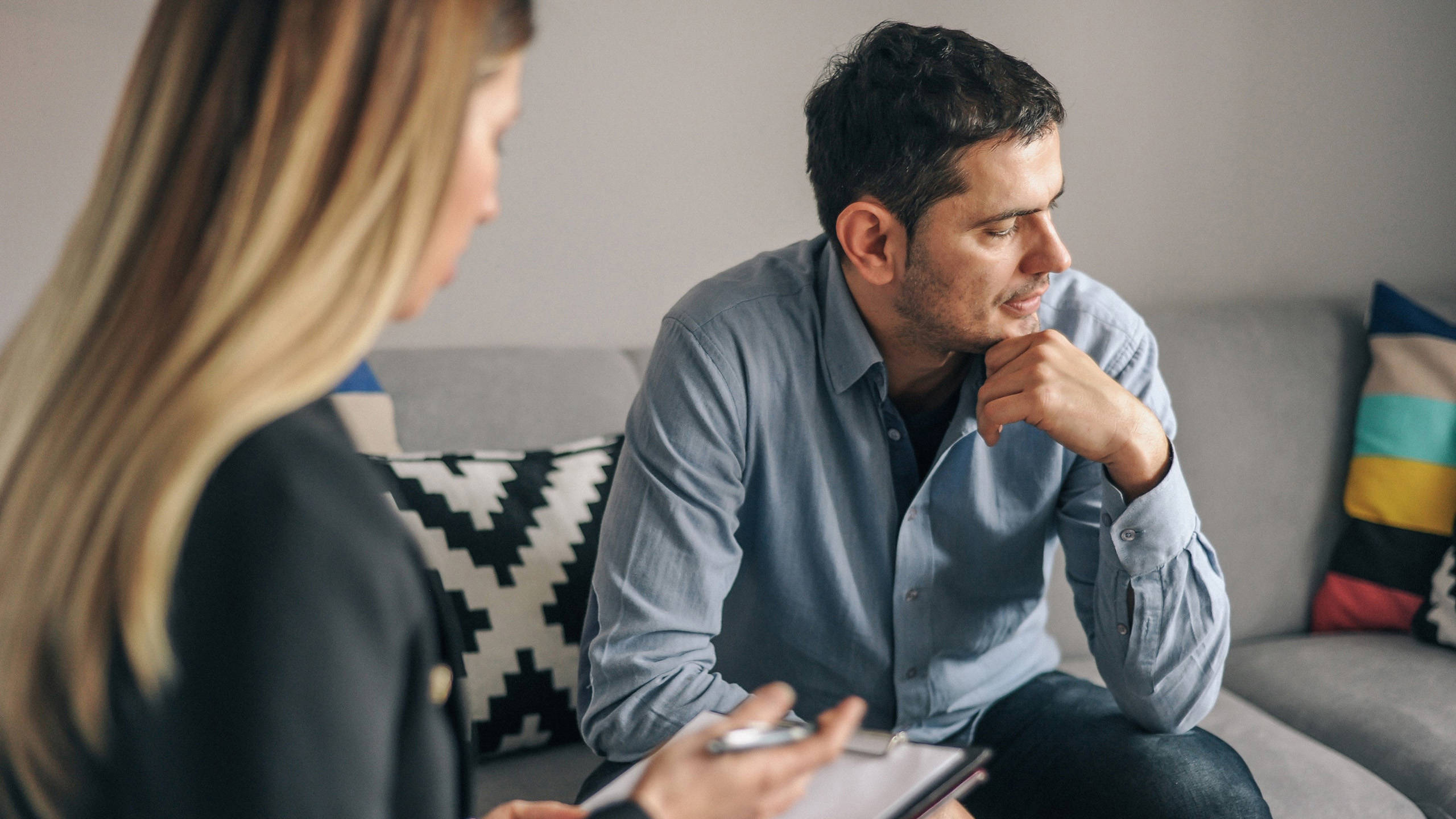 A woman taking notes and a man sitting on a couch